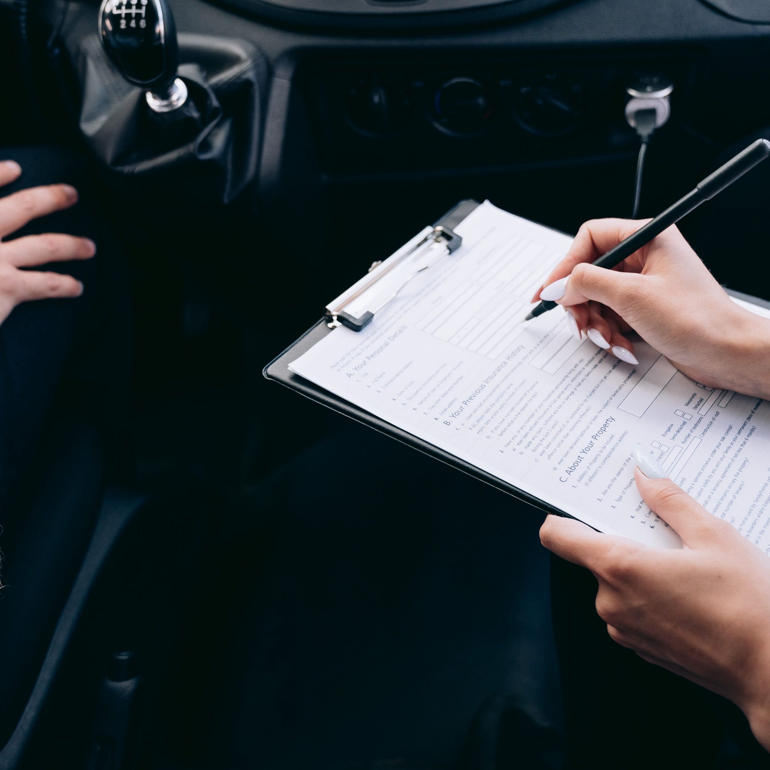 Person füllt im Auto ein Formular aus als Symbol für Unfallaufnahme, Nutzungsausfall, Mietwagenkosten und Versicherungsprüfung